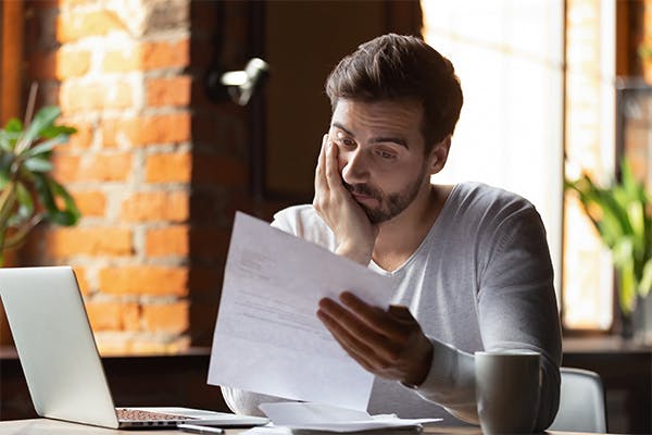 Confused-frustrated-young-man-reading-letter-in-cafe,-debt-notification