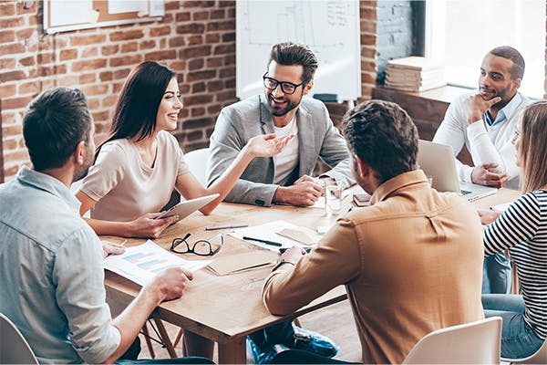 https://tower.toptrustedfunds.com/wp-content/uploads/2023/04/Young-beautiful-woman-gesturing-and-discussing-something-with-smile-while-her-coworkers-listening-to-her-sitting-at-the-office-table.jpg