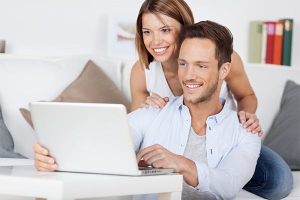 Img of Cheerful couple searching something on laptop at home